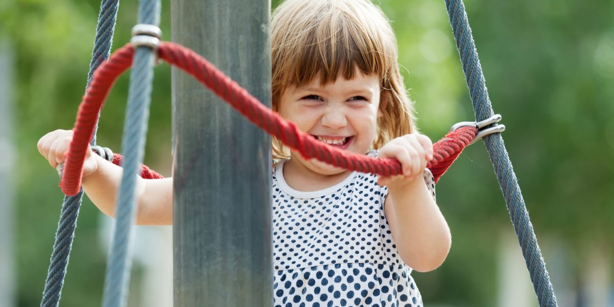 laughing girl climbing at ropes on playground